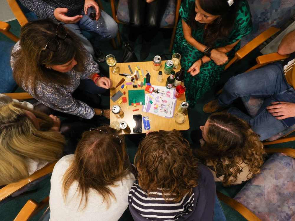 An overhead image of a group of people crowded around a table covered with lego pieces