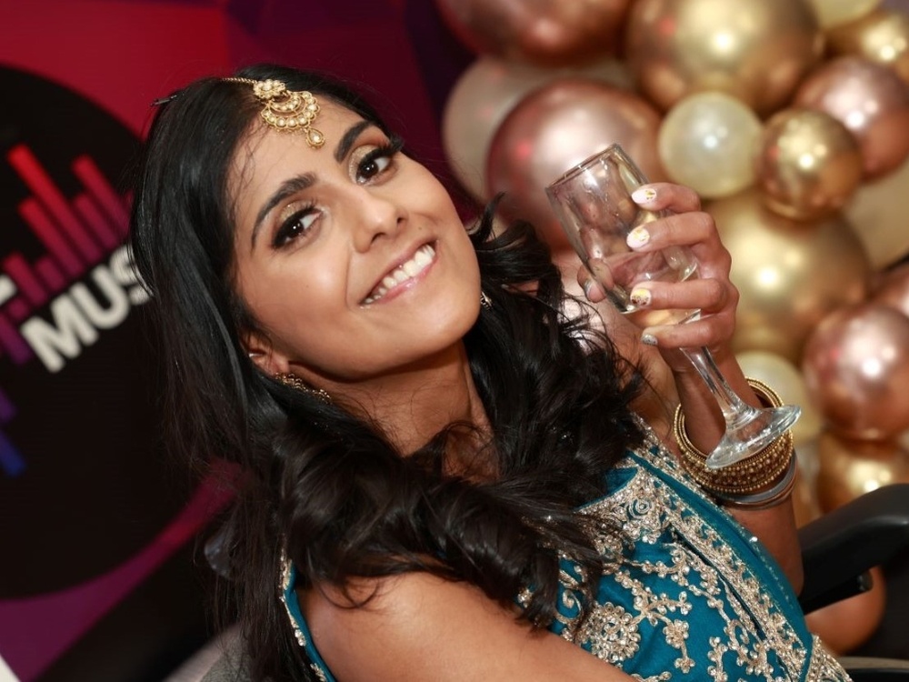 A lady smiling and holding up a glass of fizz