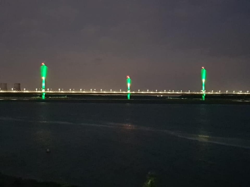 The Mersey Gateway Bridge lit up green in the darkness