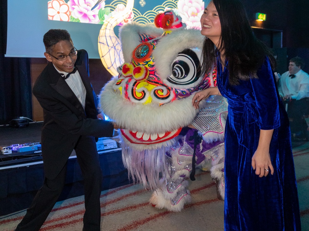 Two guests at the Lily ball laughing with a dancing Chinese dragon
