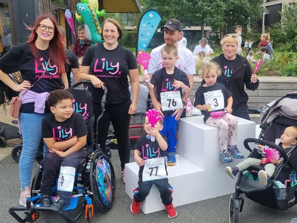 A group of adults and children in Lily tops holding running numbers and smiling