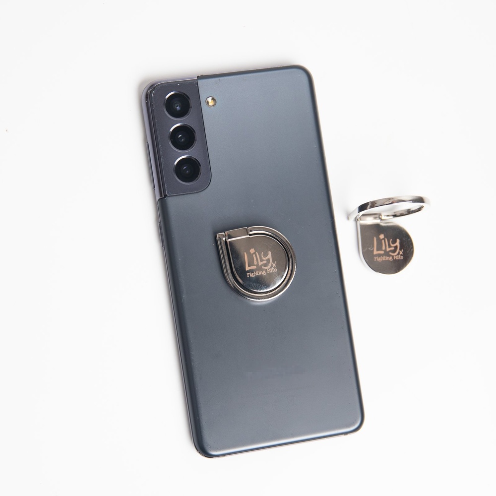 The back of a smartphone with a metal ring holder attached. The middle of the ring features the Lily Foundation logo.