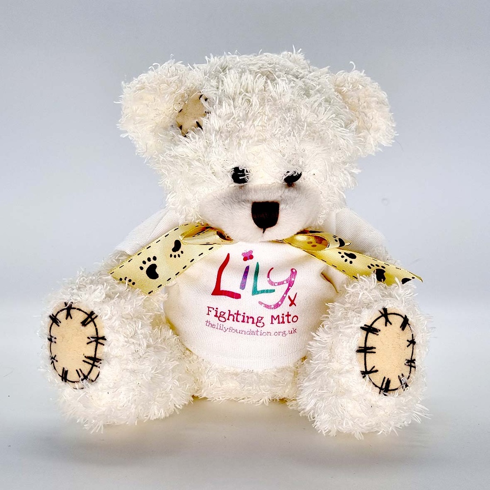 A white teddy bear with a bow and a white t-shirt featuring the Lily Foundation logo and the words fighting mito.