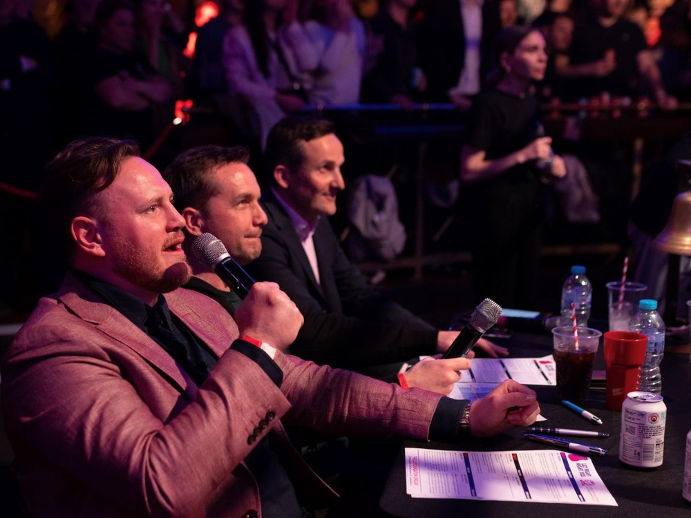 Commentators sit on the sidelines with microphones at the Lily Fight Night