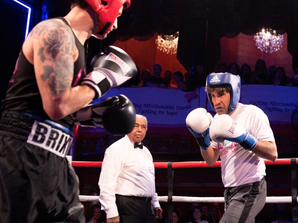 Two boxers fighting in the ring with the referee behind