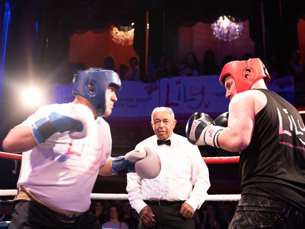Two boxers square up at Lily fight night while the referee watches