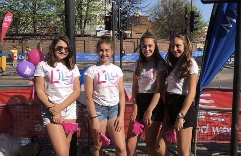 Becca and three friends wearing Lily t-shirts as a race cheer squad with pink clappers