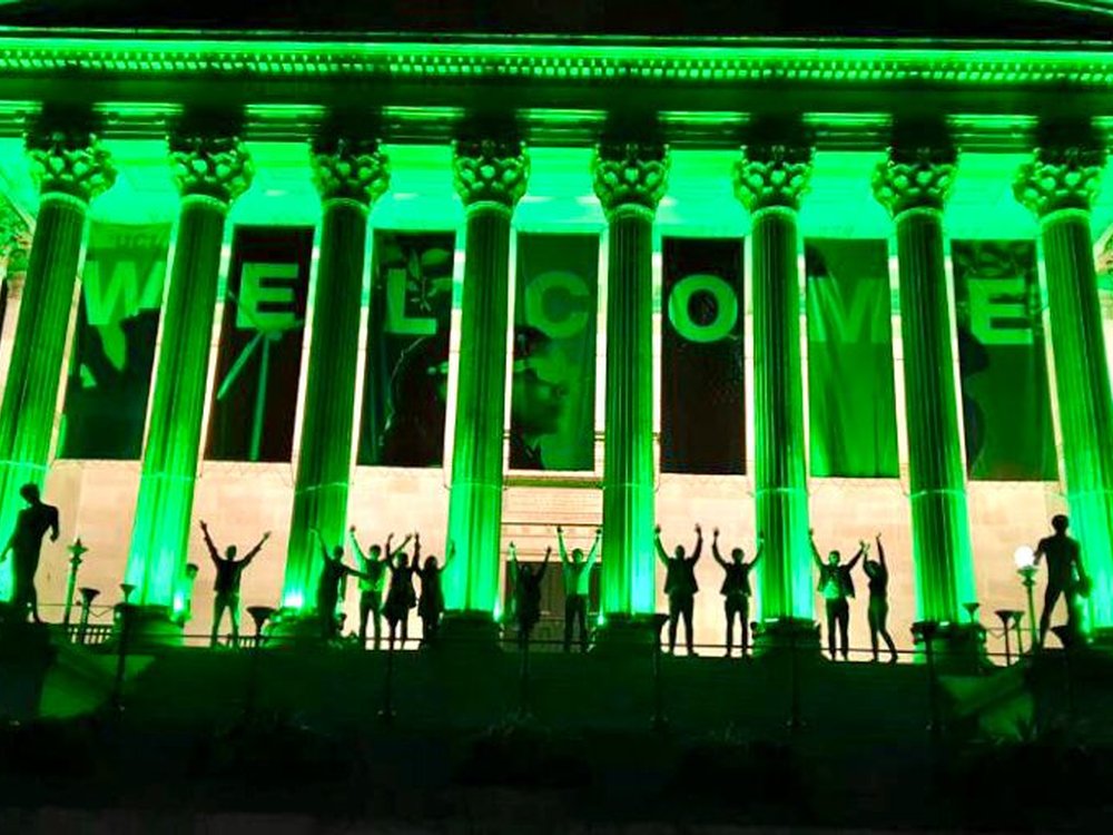 A grand looking building is lit up with green lights
