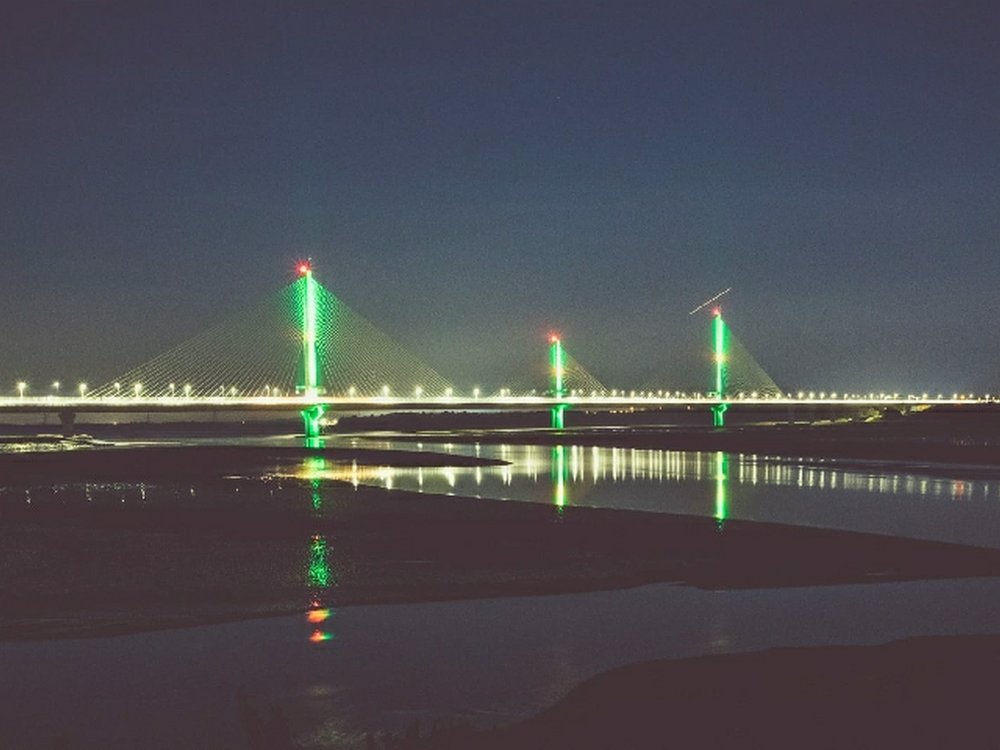 A bridge at night lit up with green lights