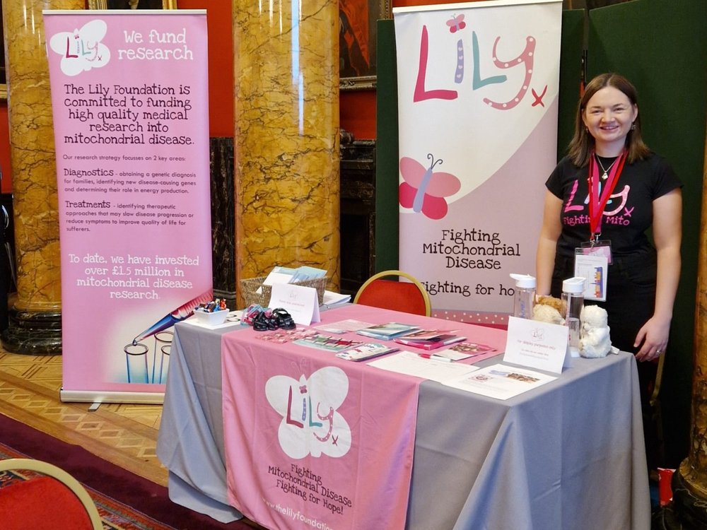 A member of the Lily Foundation team stands beside an awareness stand for the charity