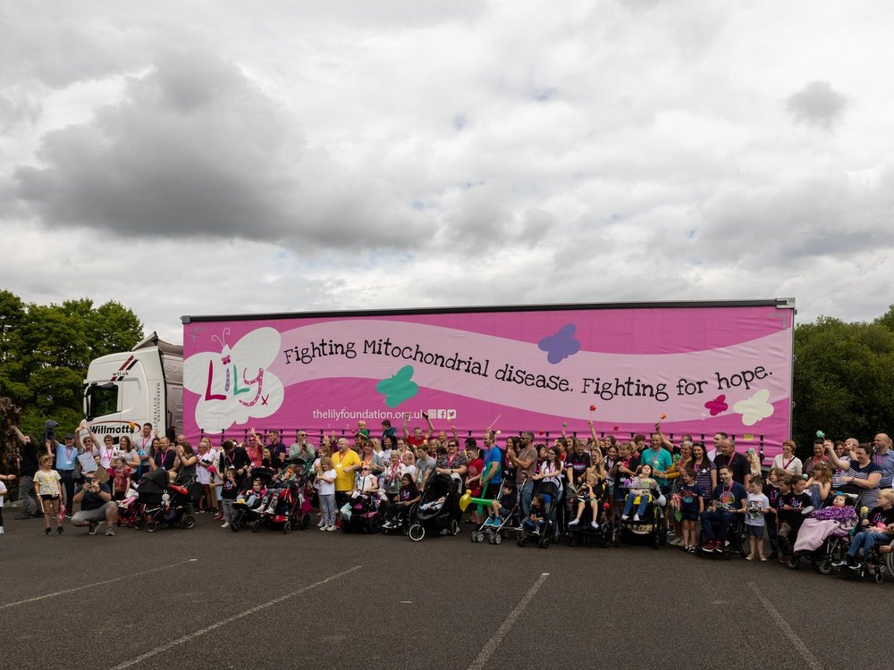 A large group of adults and children in front of a large lorry with a Lily logo