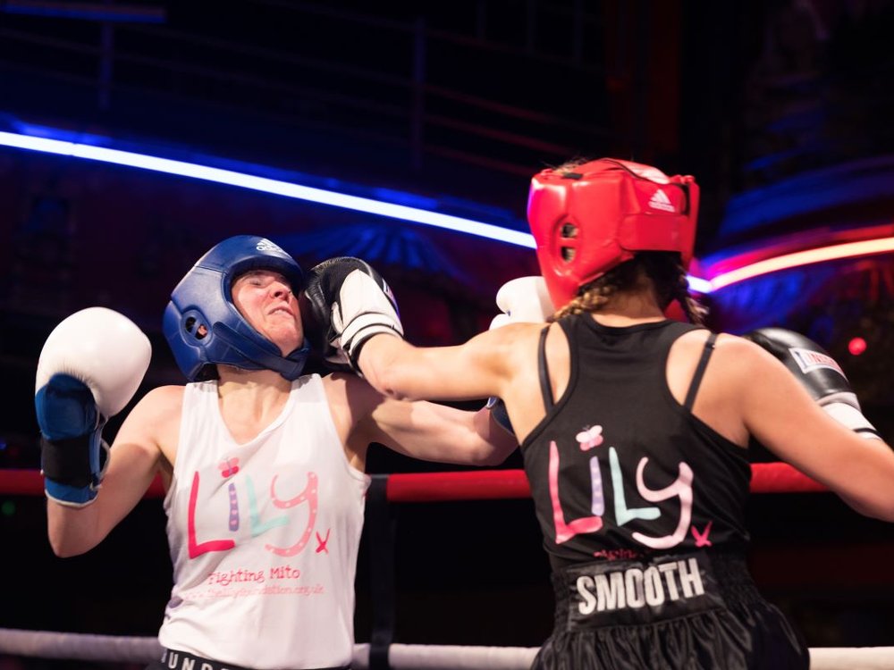 Two women boxing and wearing Lily Foundation branded vests