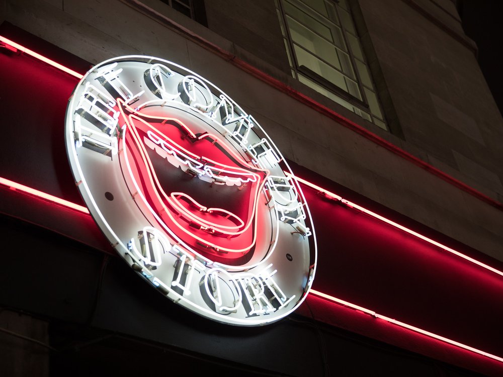 A round sign with a large red opened mouth with Comedy Store around the edge