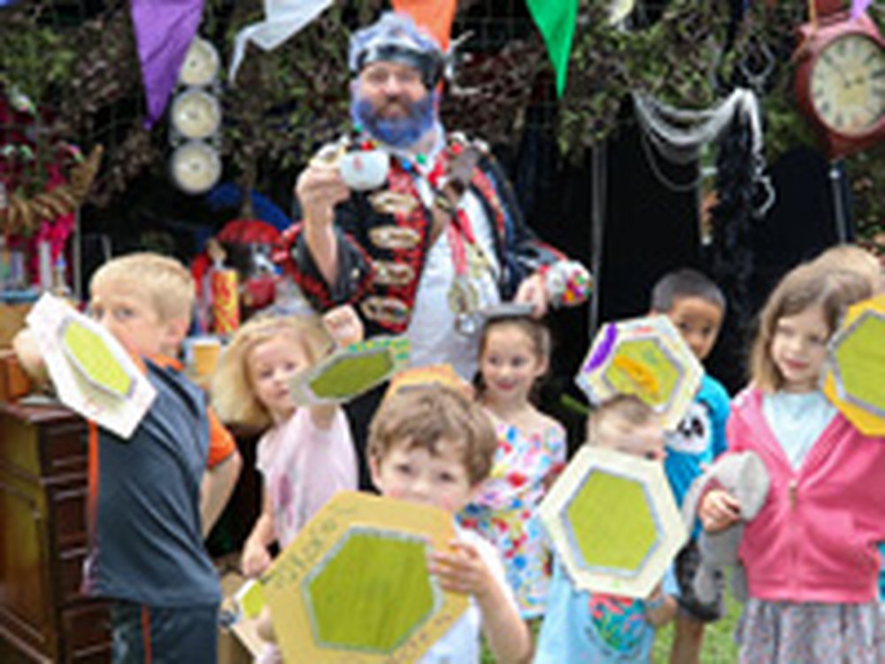 A group of children holding up green hexagons. Beind them is a man dressed as a pirate