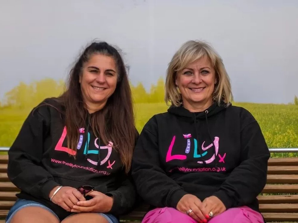 Lily founder Liz and fundraiser Sarah wearing Lily hoodies and sitting side-by-side