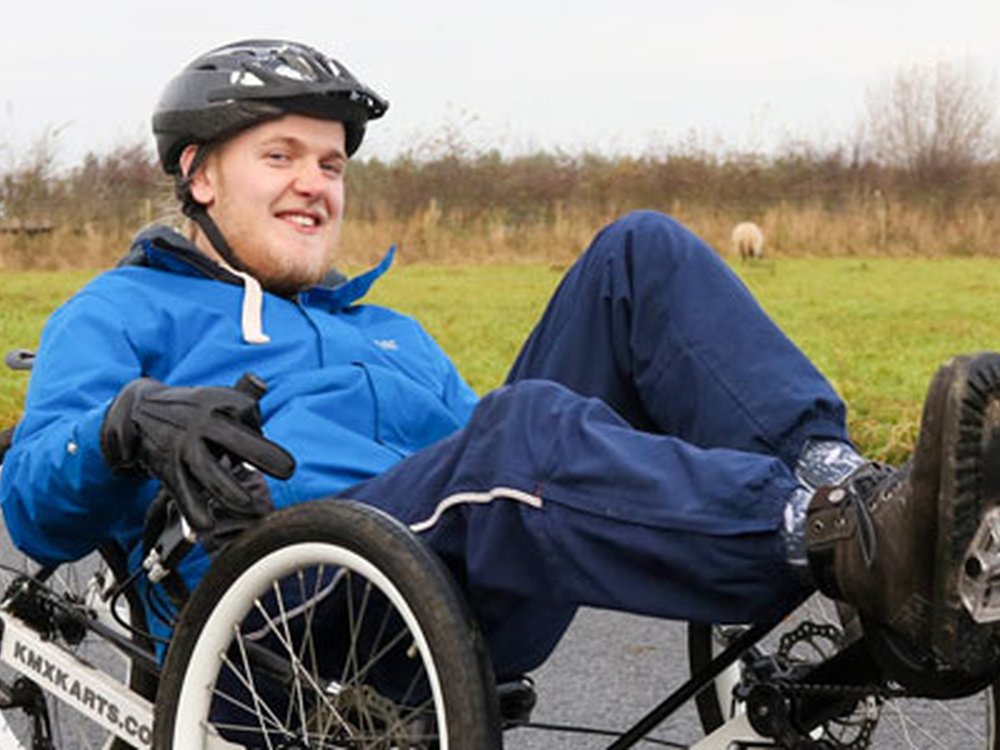 Young adult mito warrior Harry outside on a recumbent bicycle
