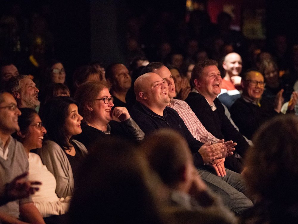 A row of people sitting in the audience at the Lily Foundation Comedy Night, laughing