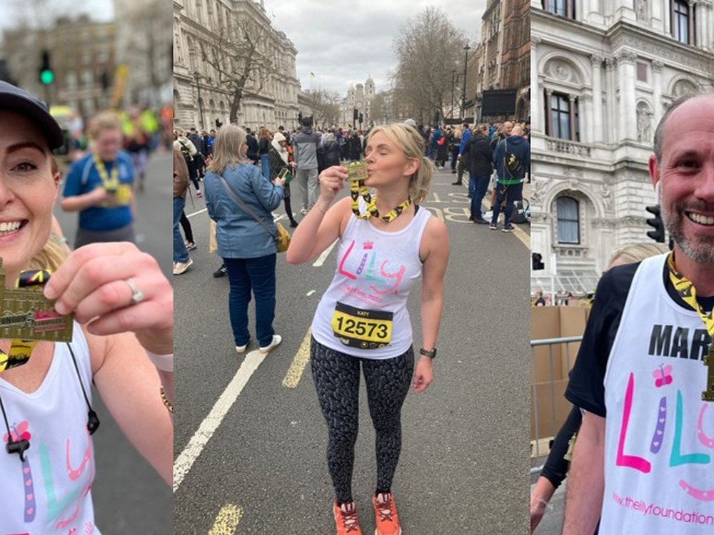 Lady in a Lily Foundation running vest and black leggings standing in a London street and kissing her medal