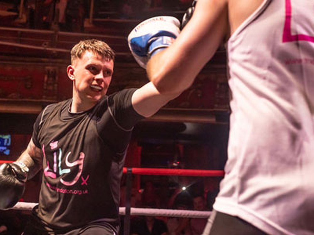 Tow boxers in a ring wearing Lily Foundation vests and throwing punches at the Lily Fight Night