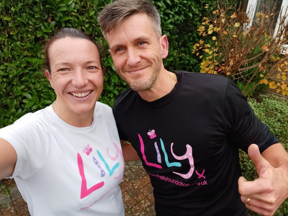 A man and a lady standing close together taking a selfie and wearing Lily Foundation t-shirts