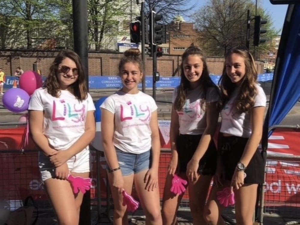 Becca and three friends wearing Lily t-shirts as a race cheer squad with pink clappers