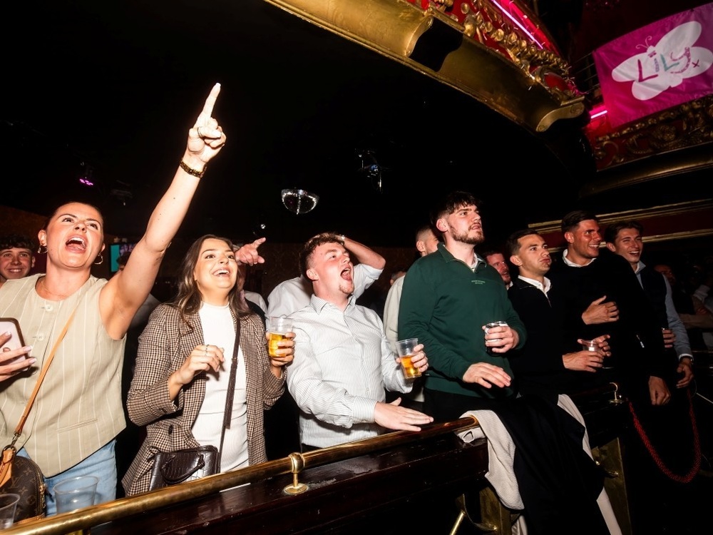 The crowd standing up at their seats in the Clapham Grand