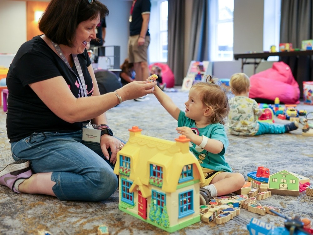 A toddler engages in play with a volunteer at the Lily weekend