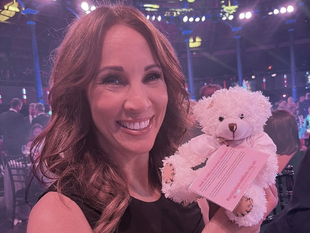 A lady holding a Lily-branded teddy and smiling at the camera
