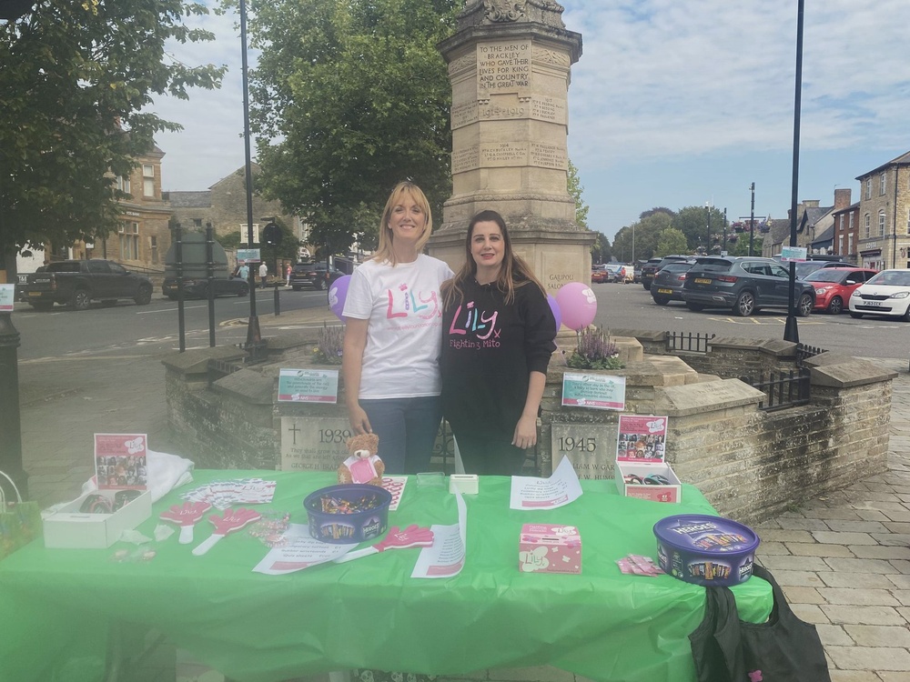 Two ladies in Lily branded tops stand behind a table filled with leaflets