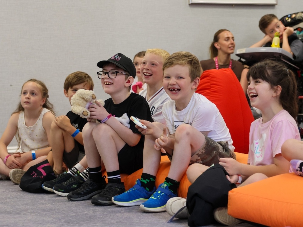 A group of young children sitting on the floor laughing