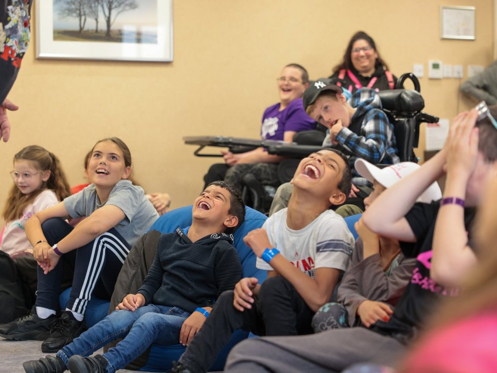 A group of children sitting on bean bags throwing their heads back with laughter