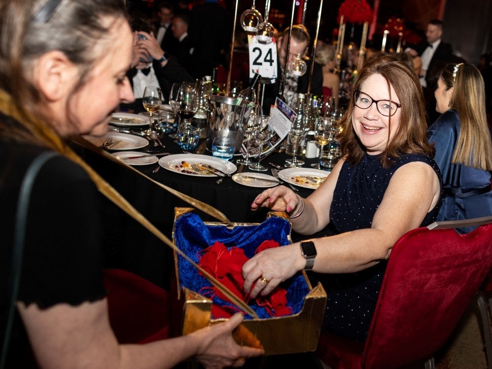 A guest in a black dress at a table chooses a lucky dip raffle bag
