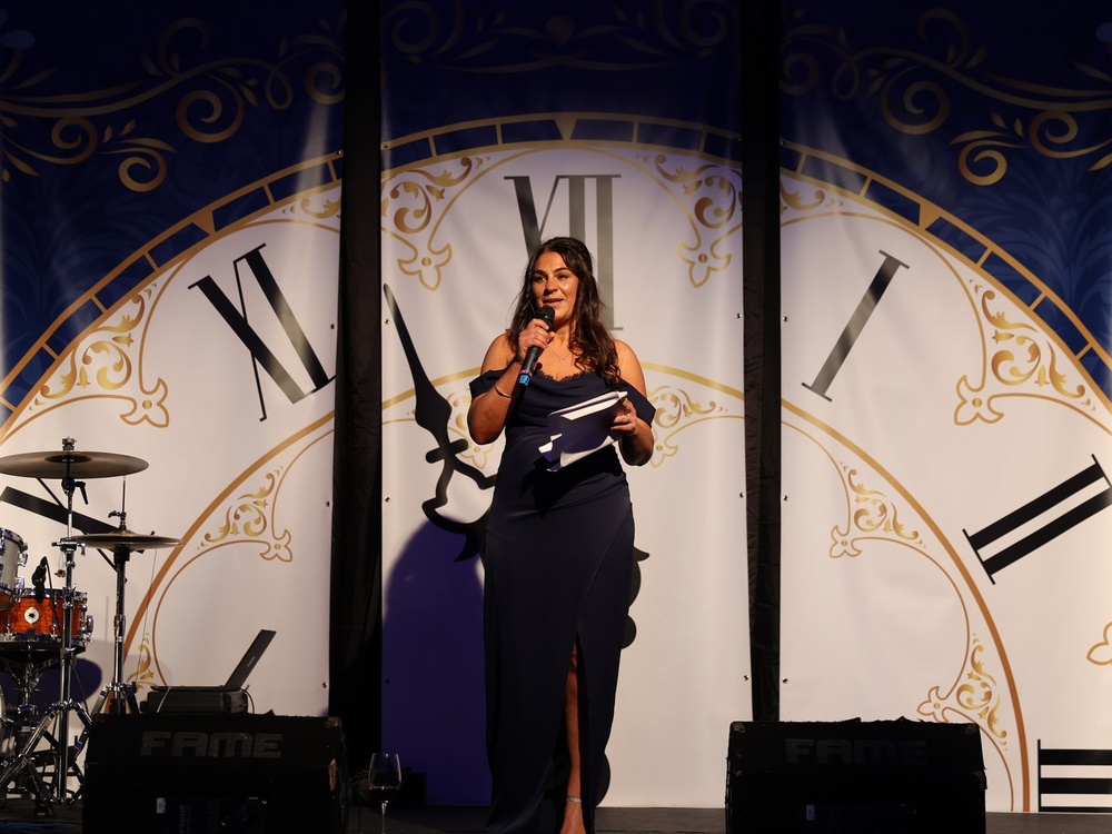 Lily founder Liz standing on stage in front of a large clock