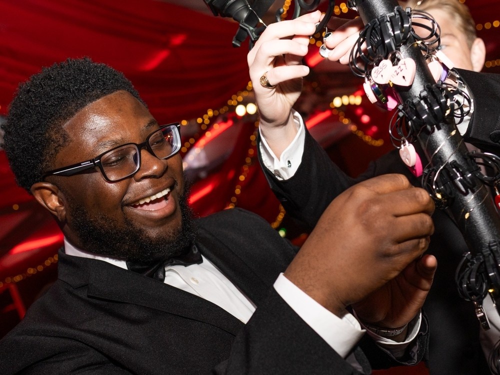 A man in a black tuxedo locking a padlock to a lamppost at the Lilt ball