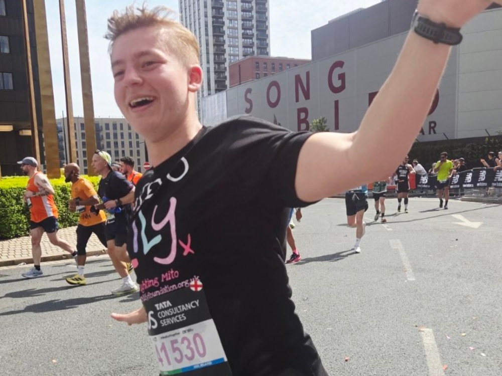 A man in a Lily t-shirt at the London marathon smiling and waving