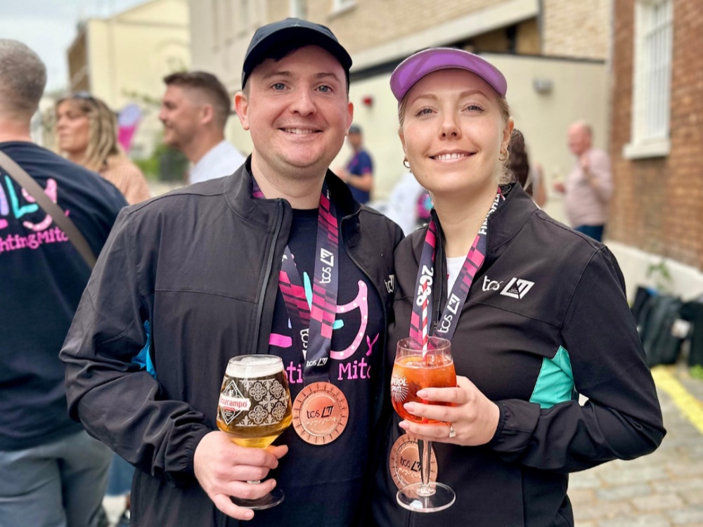 A man and a lady standing together in Lily tops holding their London marathon medals