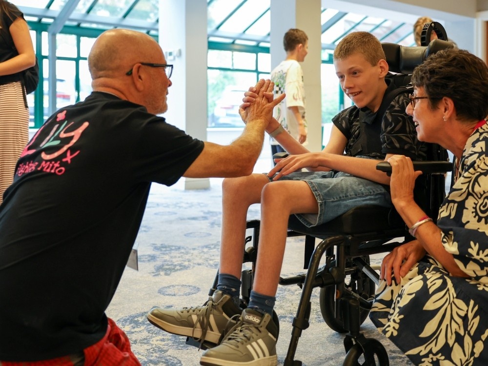 A Lily volunteer engages with a young mito patient in a wheelchair