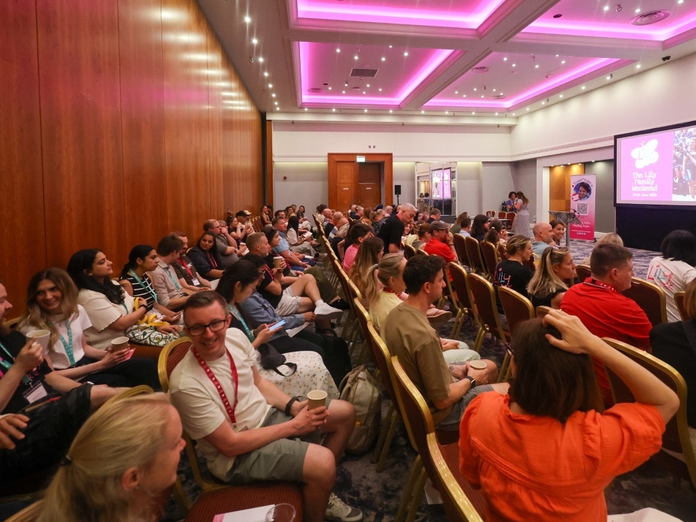 A large conference room filled with people watching a screen at the front