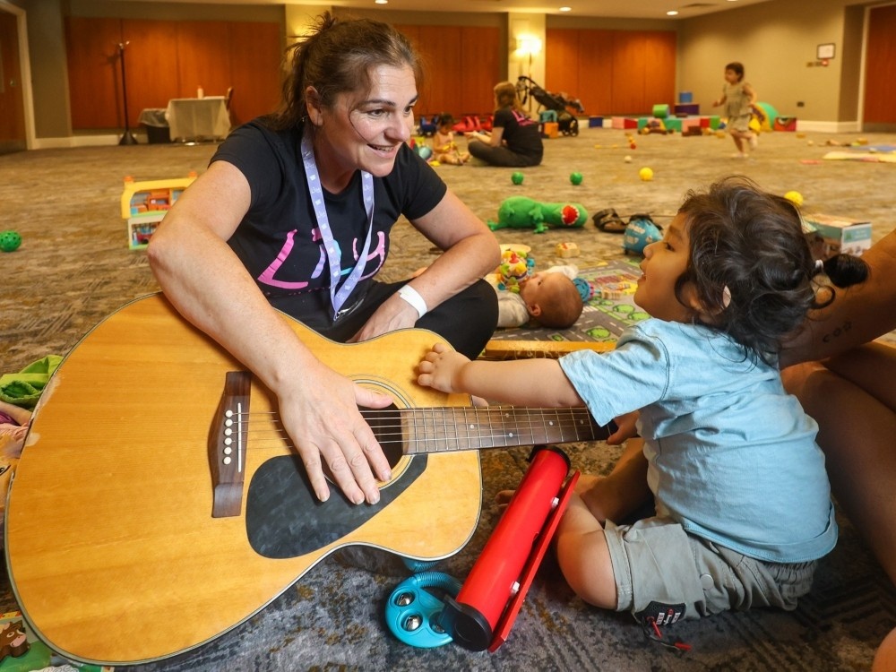 A Lily volunteer playing the guitar with a young mito patient