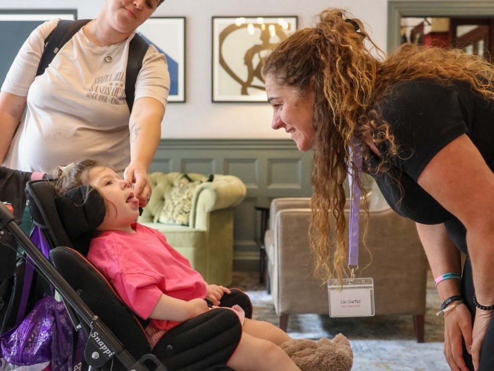 Lily founder Liz leans over a young mito patient in a buggy