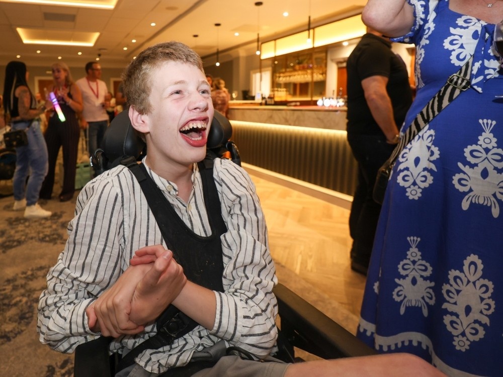 A young mitochondrial disease patient in a wheelchair laughing
