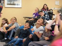 A group of children sitting on bean bags throwing their heads back with laughter