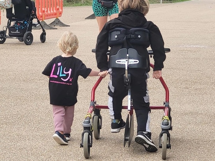 Two children, one with a frame, walking away from the camera