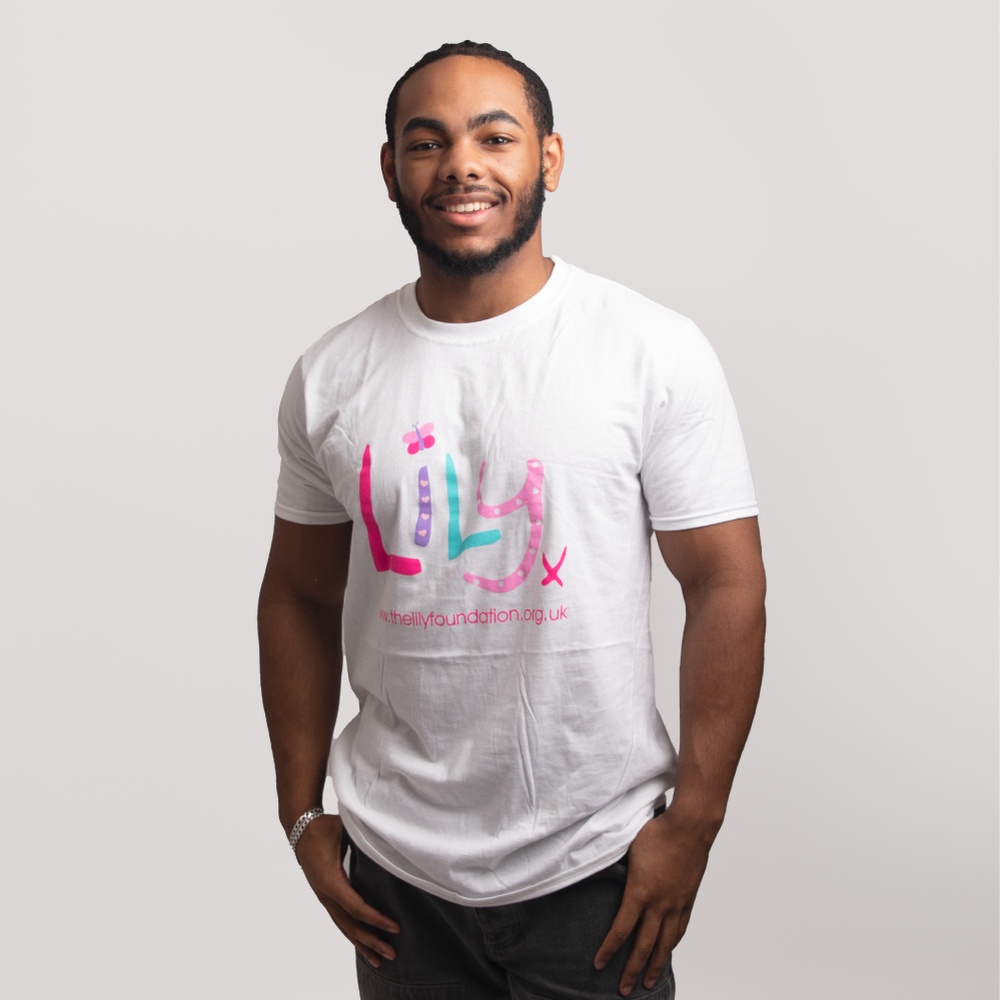 A smiling man wearing a white t-shirt featuring the Lily Foundation logo and website address.