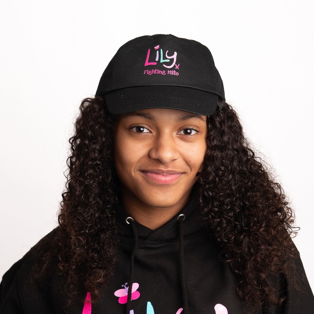 A girl in a black baseball cap featuring the Lily Foundation logo and the words fighting mito.