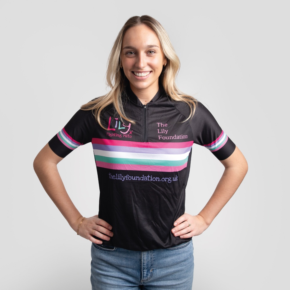 A smiling woman in a black cycling top with coloured stripes across the front, the Lily Foundation logo and website address.