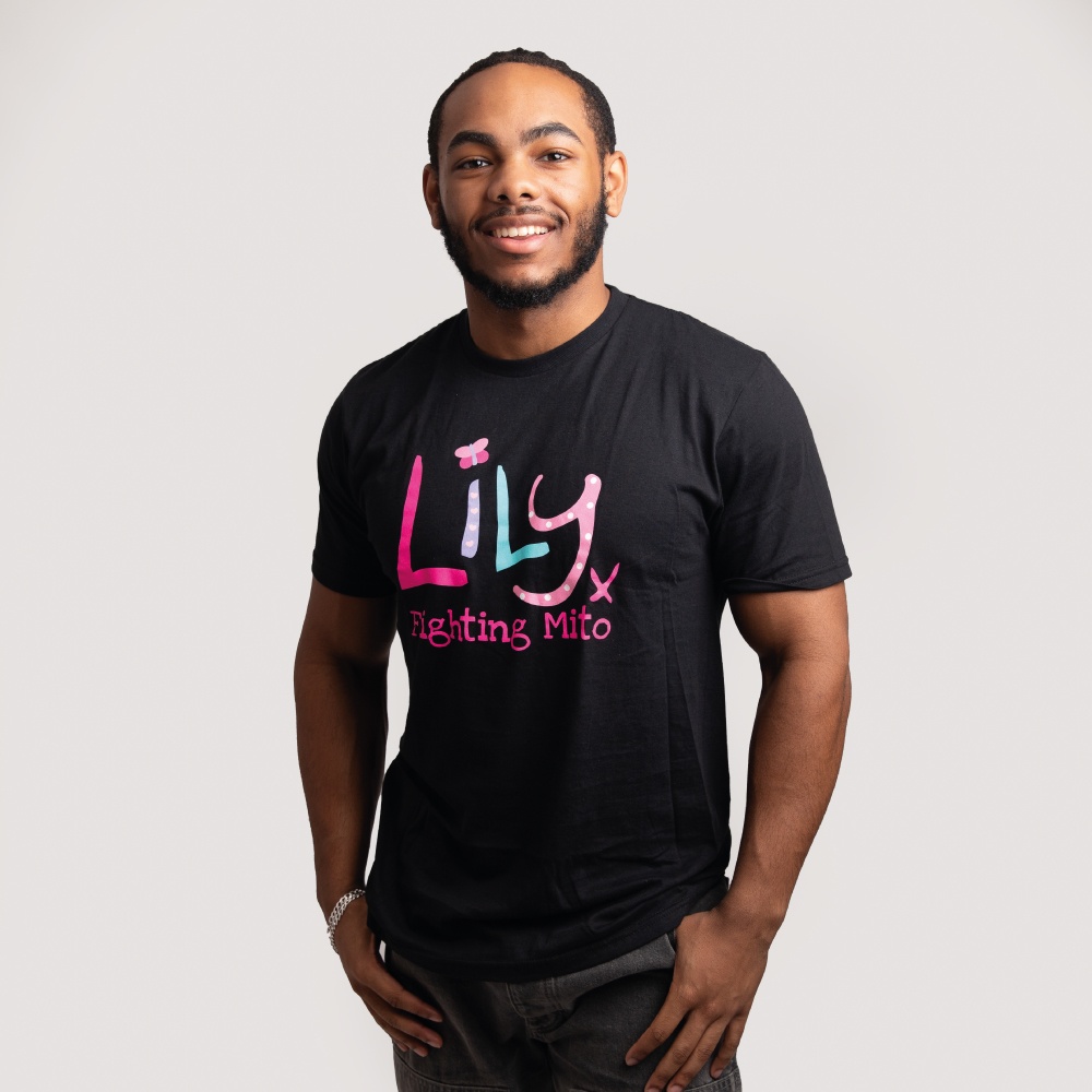 A smiling man wearing a black t-shirt featuring the Lily Foundation logo and the text Fighting mito underneath.