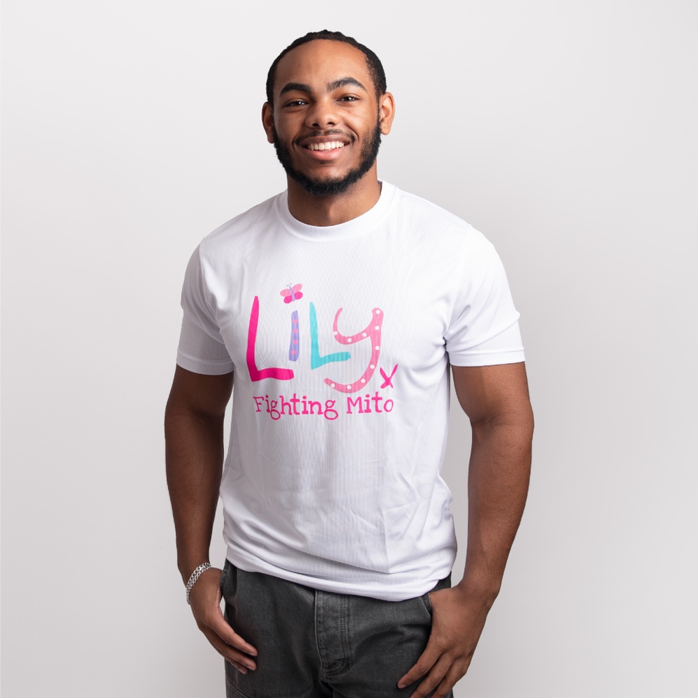 A smiling man wearing a white performance top featuring the Lily Foundation logo with fighting mito underneath.