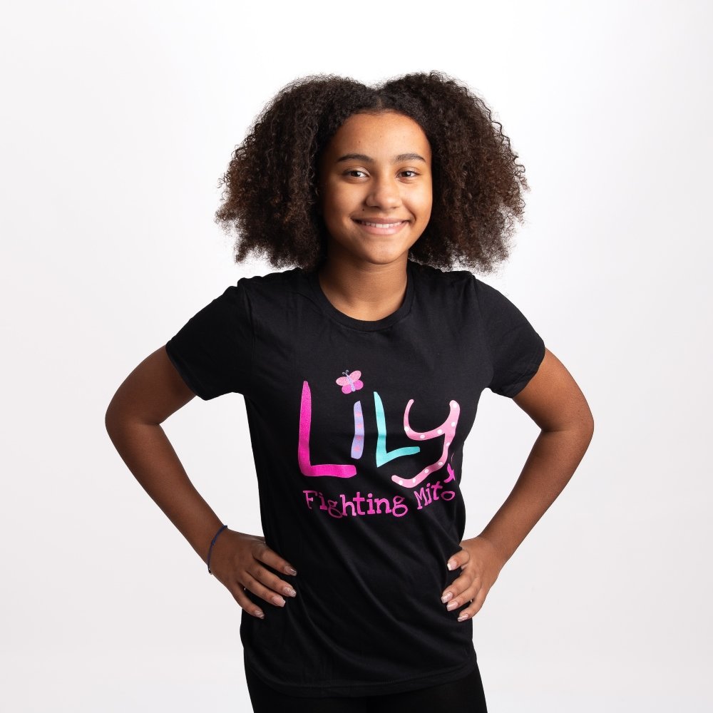 A young girl wearing a black t-shirt featuring the Lily Foundation logo and the text fighting mito.