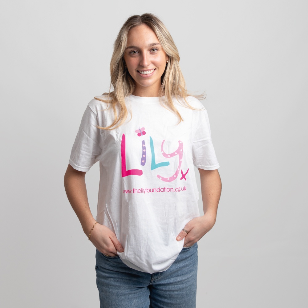 A smiling woman in a white t-shirt featuring the Lily Foundation logo and website address.